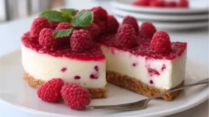 Cheesecake sans cuisson à la framboise, servi sur une assiette blanche avec framboises fraîches.
