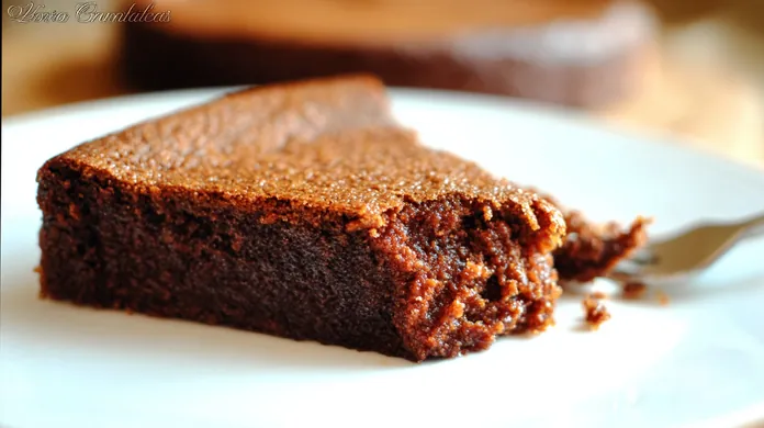 Part de gâteau au chocolat fondant de Cyril Lignac sur assiette blanche, texture moelleuse et brillante.
