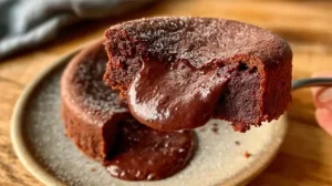 Part de fondant au chocolat méga coulant, texture brillante et moelleuse, servie tiède sur assiette claire.