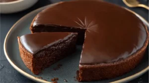 Gâteau moelleux au chocolat à la texture fondante et au glaçage brillant sur assiette sombre.